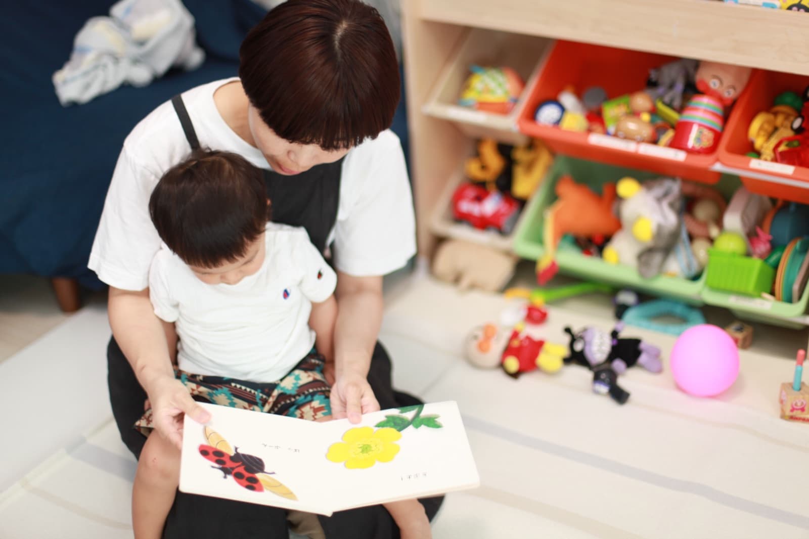 ottene. シッターのひざの上で絵本を見る子ども